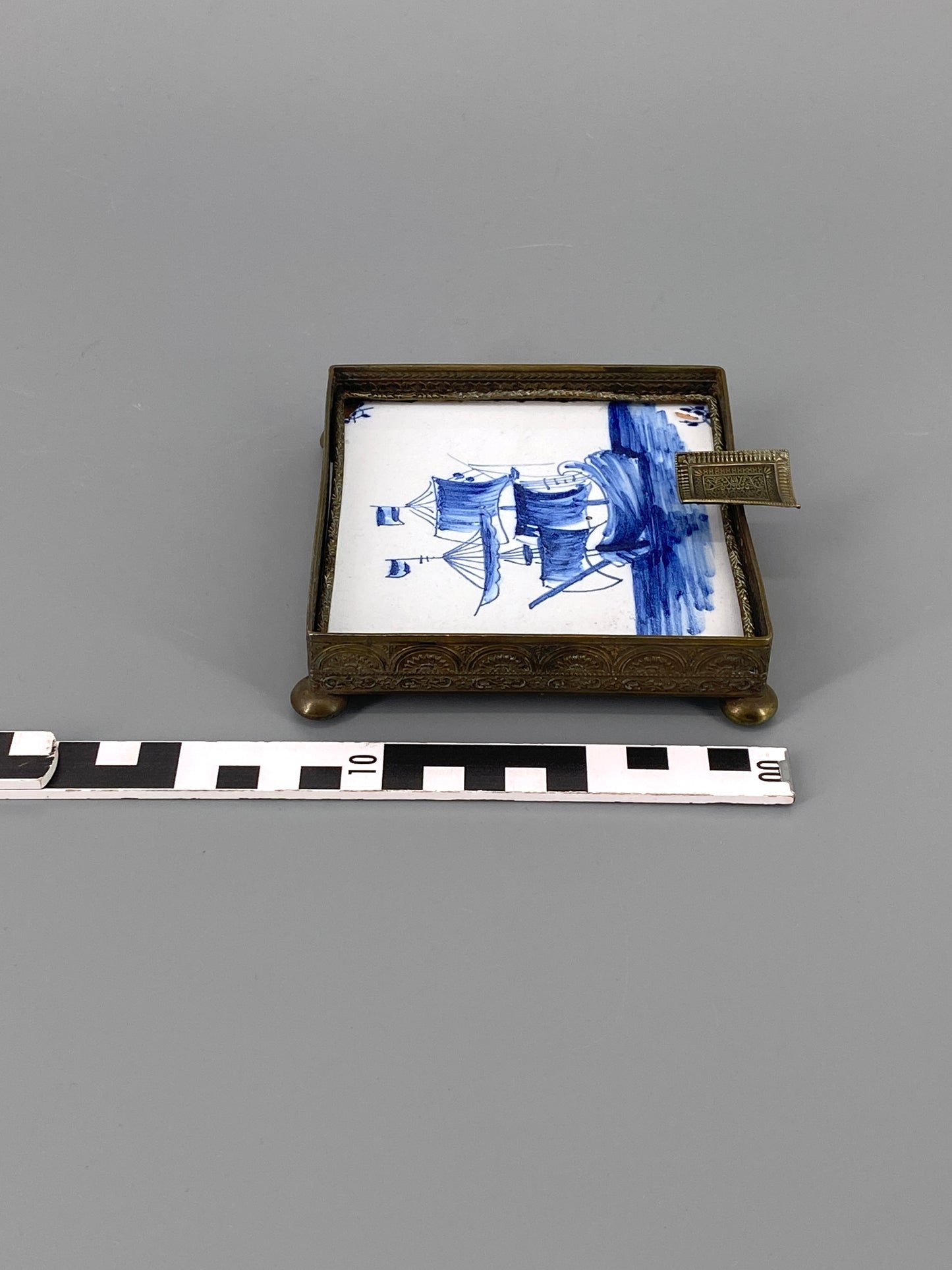 Fliese mit Schiffsmotiv gefasst in verziertem Messingrahmen, Aschenbecher / Ablage